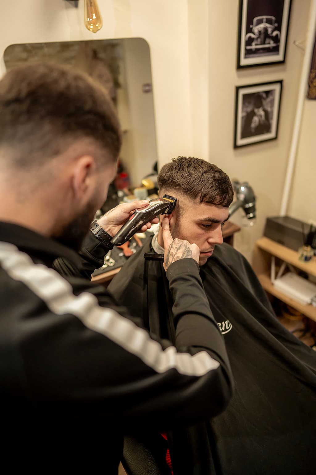 A barber lining up a client's cut with clippers